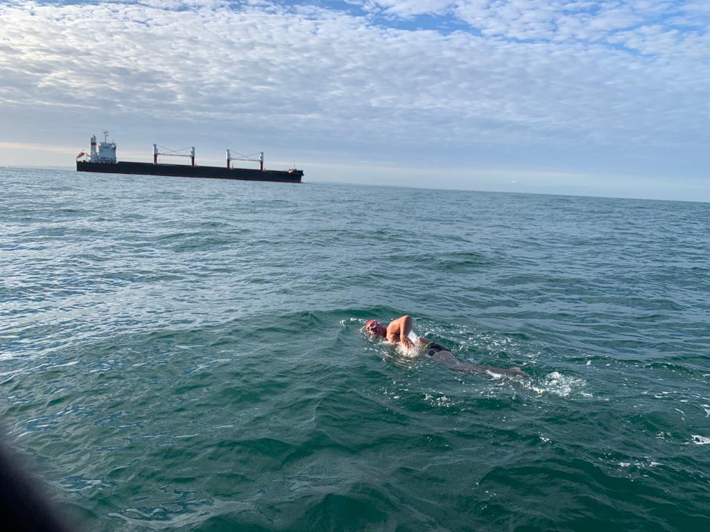 A swimmer with the french shipping channel in the background.
